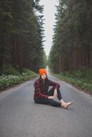Charming brunette sitting on a path surrounded by wild nature, enjoying the feeling of freedom and fresh air. Lush greenery and tall trees, symbolizing adventure and tranquility in nature photo