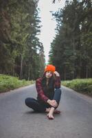 Charming brunette sitting on a path surrounded by wild nature, enjoying the feeling of freedom and fresh air. Lush greenery and tall trees, symbolizing adventure and tranquility in nature photo