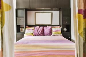 A bed with colorful bedding and a mirror photo