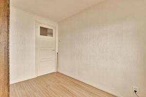 A room with a door and wooden flooring photo