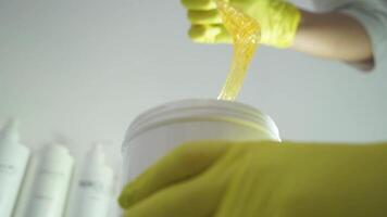Depilation master woman scoop up the sugar paste right before the procedure of epilation video