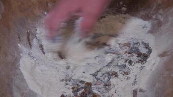 An ancient way of making bread in the countryside. A man is stirring the dough with his hands in an antique dish. video