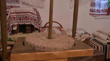 The ancient Quern stone hand mill with grain. The man grinds the grain into flour with the help of a millstone. Men hands on a millstone. Old grinding stones turned by hands video