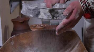 The ancient Quern stone hand mill with grain. The man grinds the grain into flour with the help of a millstone. Men hands on a millstone. Old grinding stones turned by hands video