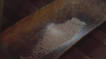 The ancient Quern stone hand mill with grain. The man grinds the grain into flour with the help of a millstone. Men hands on a millstone. Old grinding stones turned by hands video