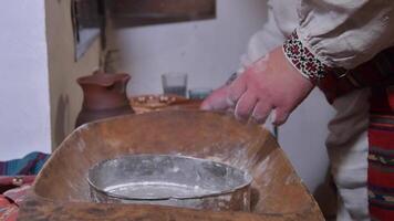 The ancient Quern stone hand mill with grain. The man grinds the grain into flour with the help of a millstone. Men hands on a millstone. Old grinding stones turned by hands video