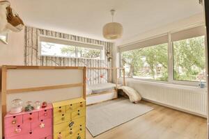 A small room with a bed, a toy box and a window photo