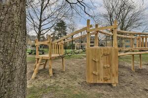 A wooden playground structure with a tree in the background photo