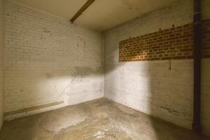 An empty room with a brick wall and a pipe photo