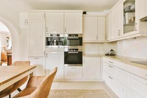 A white kitchen with a table and chairs photo