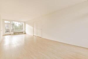 An empty room with hardwood floors and a large window photo