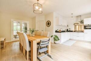 A white kitchen with a wooden table and chairs photo