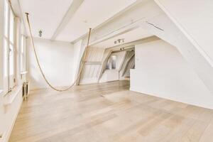 An empty room with wooden floors and a rope hanging from the ceiling photo