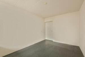 A empty room with a door and a gray floor photo