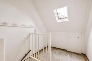 An empty attic with a skylight and stairs photo