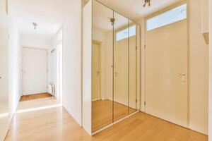 A hallway with a mirror and wooden floors photo