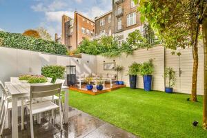 A backyard with a table and chairs, a lawn and artificial grass photo