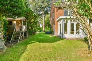 A large house with a large yard and a tree photo
