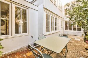 A patio with a table and chairs in front of a window photo