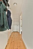A hallway with a coat rack and a wooden floor photo