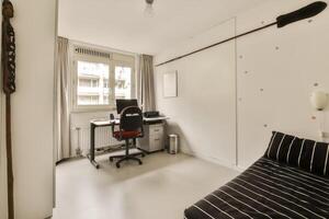 A small room with a desk, chair and a computer photo