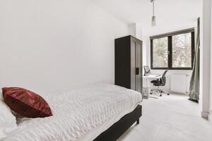 A bedroom with a white bed and a desk photo