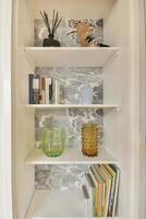 A white shelf with books and vases on it photo