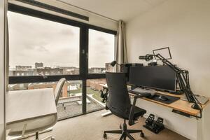A desk with a computer and chair in front of a window photo