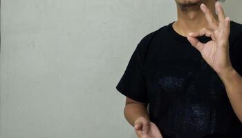 young man showing hearing gesture in sign language to communicate photo