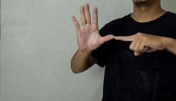 young man showing hearing impaired gesture in sign language to communicate photo