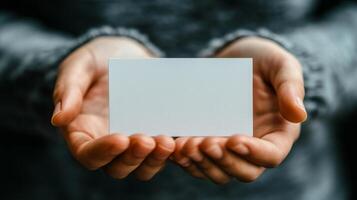 Person holding a blank business card in hands with a soft background during daylight photo