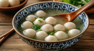 Warm bowl of homemade dumpling soup garnished with fresh green onions in a rustic kitchen setting photo