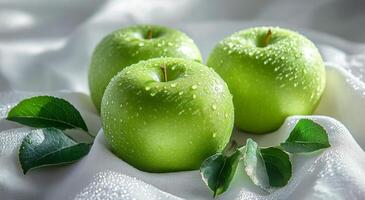 Freshly washed green apples resting on leaves with morning dew in a bright, natural setting photo