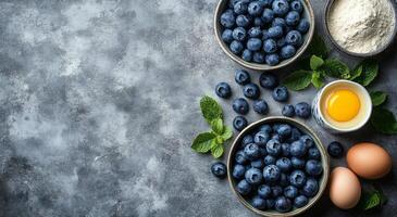 Fresh blueberries on a countertop with flour, egg, and mint leaves during a cooking session photo