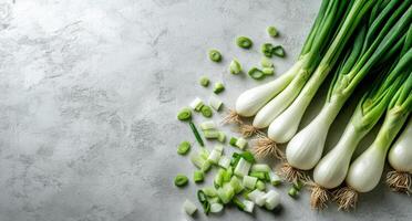 Freshly chopped green onions arranged beside whole scallions on a light textured surface photo