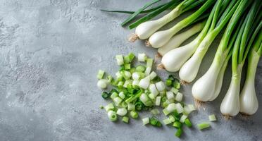 Freshly chopped green onions arranged beside whole scallions on a light textured surface photo