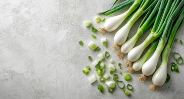 Freshly chopped green onions arranged beside whole scallions on a light textured surface photo