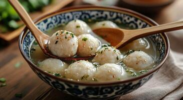 Warm bowl of homemade dumpling soup garnished with fresh green onions in a rustic kitchen setting photo