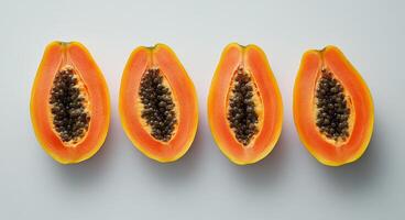 Fresh papayas sliced open, showcasing vibrant orange flesh and black seeds on a white surface photo