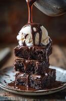 Delicious brownie stack topped with vanilla ice cream and drizzled chocolate sauce photo