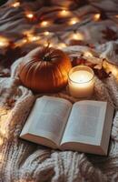 Cozy autumn evening with a pumpkin, candle, and an open book by the window on a warm blanket photo