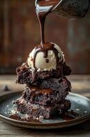 Delicious brownie stack topped with vanilla ice cream and drizzled chocolate sauce photo
