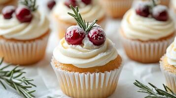 Delicious holiday vanilla cupcakes decorated with cranberries and rosemary on a festive table photo