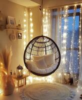 Cozy hanging chair surrounded by warm fairy lights in a modern living space at dusk photo