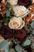 Beautiful arrangement of red and cream roses with greenery and touches of gold in a bouquet photo