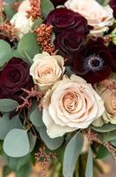 Beautiful arrangement of red and cream roses with greenery and touches of gold in a bouquet photo