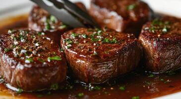 Savory grilled steak strips served on a white plate with rich sauce and herbs photo