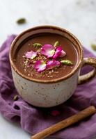 Warm spiced cocoa topped with rose petals and nuts resting on a purple cloth photo