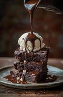 Delicious brownie stack topped with vanilla ice cream and drizzled chocolate sauce photo