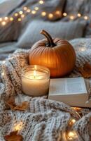 Cozy autumn evening with a pumpkin, candle, and an open book by the window on a warm blanket photo
